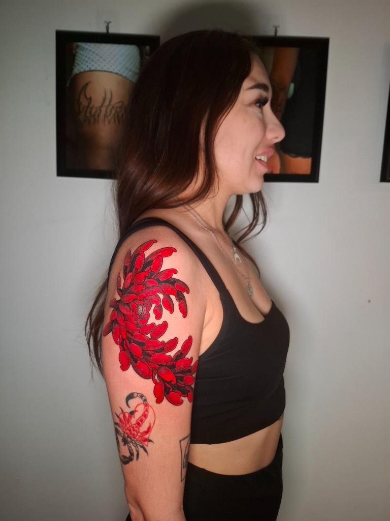 Bold red floral tattoo on shoulder — Japanese-inspired colour work
