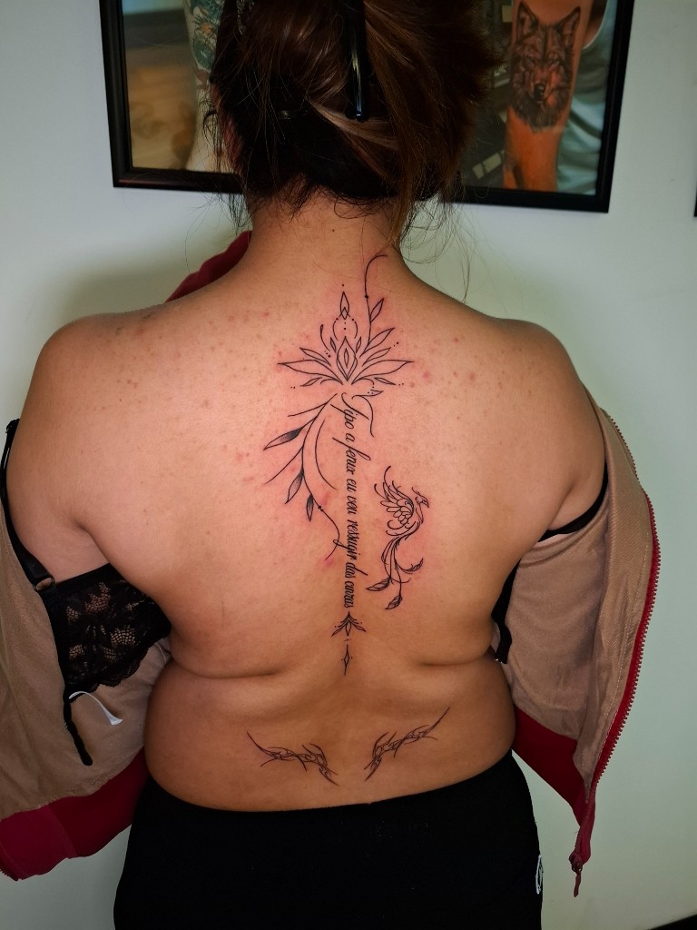 Fine-line spine piece with lotus, script, and phoenix