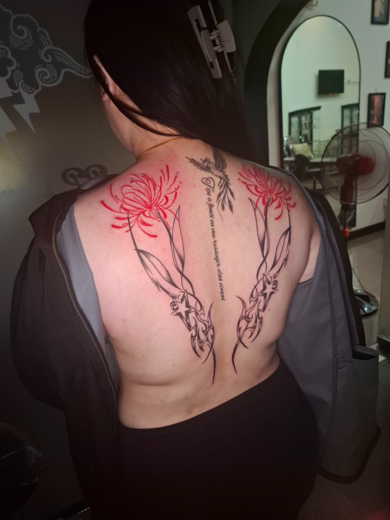 Red spider lilies, tribal flow, and script on upper back